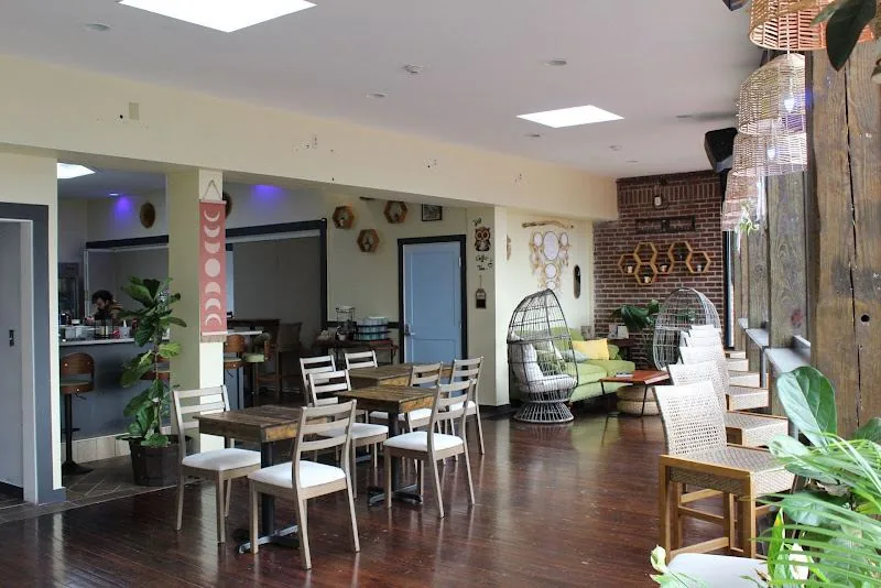 Crescent Moon Cafe interior — reclaimed wood tables, hanging lanterns, exposed brick, and lush plants