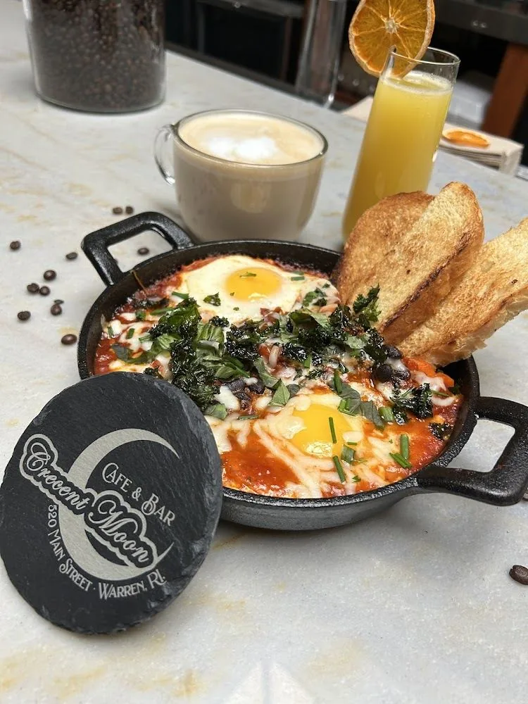 Shakshuka in cast iron skillet with branded slate coaster