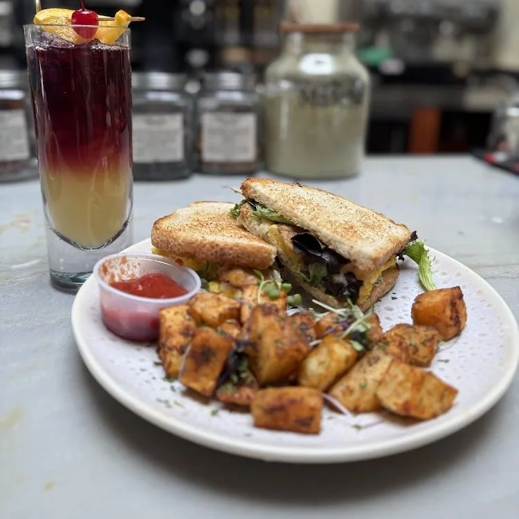 Breakfast sandwich with herb potatoes and sunrise cocktail